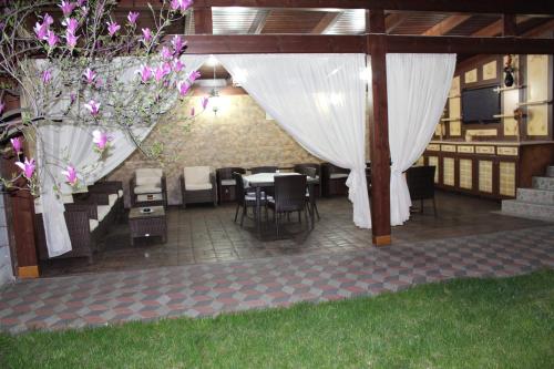 a patio with a table and chairs and white curtains at Pensiunea Normandia in Timişoara
