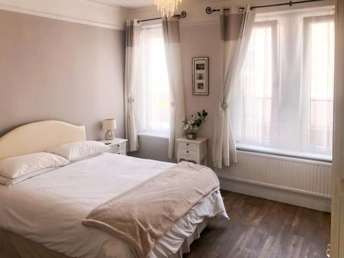 um quarto com uma cama branca e 2 janelas em Coastal Hideaway em Sandown