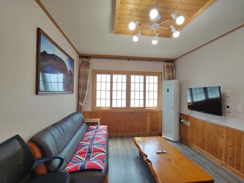 a living room with a couch and a tv at Gyulhouse Pension in Seogwipo