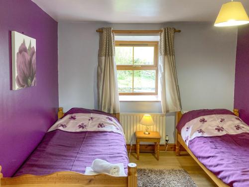 two beds in a room with purple walls and a window at The Milking Parlour in Brompton