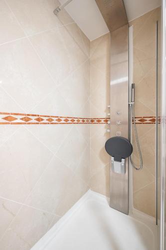 a shower with a black stool in a bathroom at La Grande Palmeraie - Spacieux studio avec vue mer, terrasse, port de Garavan in Menton