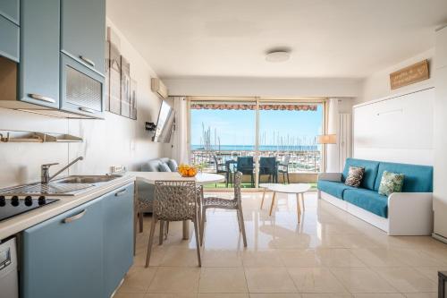 a kitchen and living room with a couch and a table at La Grande Palmeraie - Spacieux studio avec vue mer, terrasse, port de Garavan in Menton