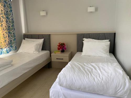 um quarto com duas camas com lençóis brancos e flores em Merve Apartments, your home from home in central BODRUM, street cats frequent the property, not all apartments have balconies , ground floor have terrace with table and chairs em Bodrum City