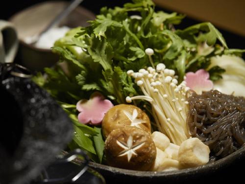 a bowl filled with greens and vegetables on a table at Ryokan Kigusuriya in Nantan city