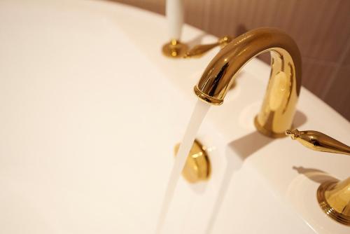 a bathroom sink with a gold faucet at Denbasta Hotel in Busan