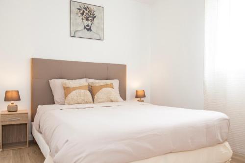sypialnia z dużym białym łóżkiem z 2 lampami w obiekcie Echappée belle Osnyssoise w mieście Osny