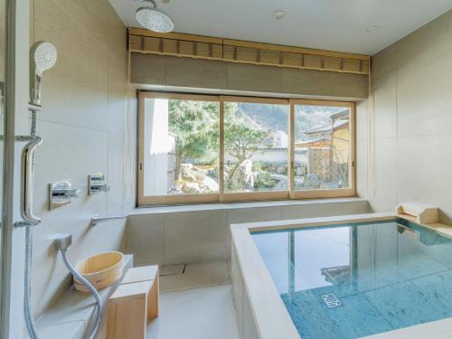 a bathroom with a tub and a swimming pool at Ryokan Kigusuriya in Nantan city