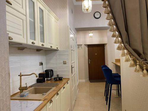 una cocina con armarios blancos, fregadero y sillas azules en Radiance Residence, en Cracovia