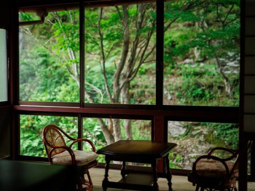 a room with a table and chairs and a window at Ryokan Kigusuriya in Nantan city