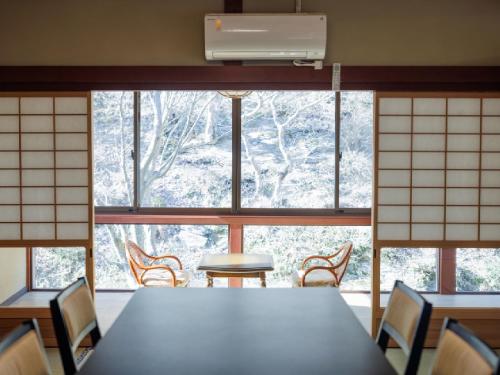 a room with a table and chairs in front of a window at Ryokan Kigusuriya in Nantan city