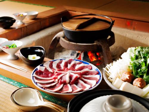a table with a plate of meat and rice at Ryokan Kigusuriya in Nantan city