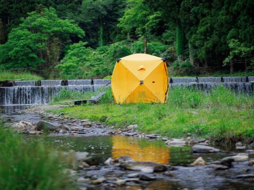 a yellow umbrella sitting in the grass next to a stream at Ryokan Kigusuriya in Nantan city