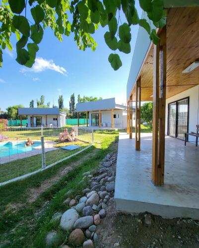 un patio trasero con piscina y una casa en Posada y Cabañas "Finca El Rincón de Lunlunta" en Mendoza