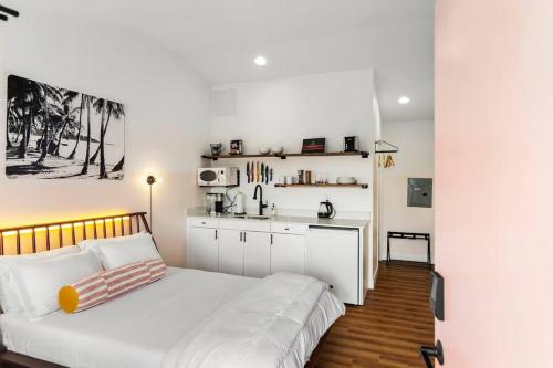 a white bedroom with a bed and a kitchen at Waiakapuhi Studio suite.ʻoluʻolu pālua in Chandler