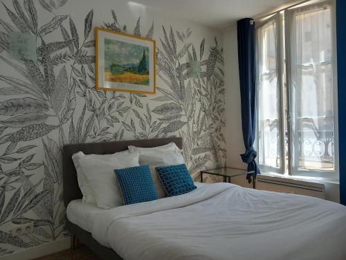 sypialnia z łóżkiem z niebiesko-białymi poduszkami w obiekcie Le Studio Versaillais w Wersalu