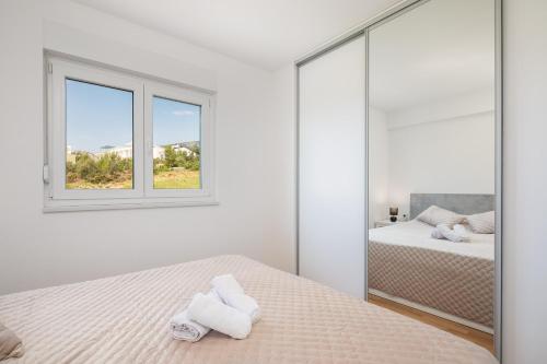 een witte slaapkamer met 2 bedden en een spiegel bij Lucas - Sea view apartment with parking in Makarska