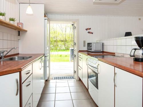 a kitchen with white cabinets and a door to a yard at 8 person holiday home in Hemmet in Falen