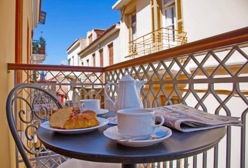 uma mesa com chávenas de café e pão numa varanda em Aetoma Hotel em Nafplio