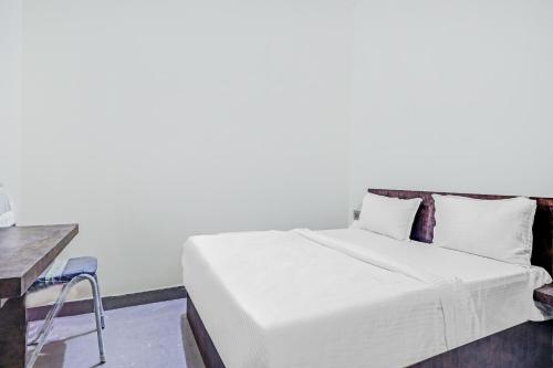 a bedroom with a white bed and a table at Collection O Hotel Dhruv Tara Inn in Patna