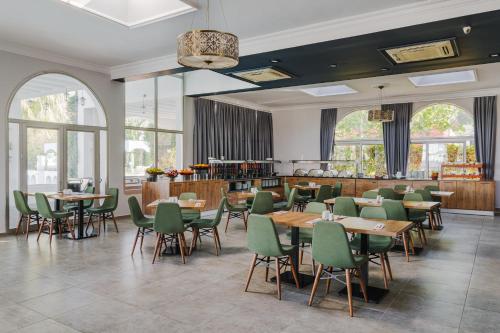 a restaurant with wooden tables and green chairs at UPTOWN Büyük Anadolu Girne Hotel in Kyrenia