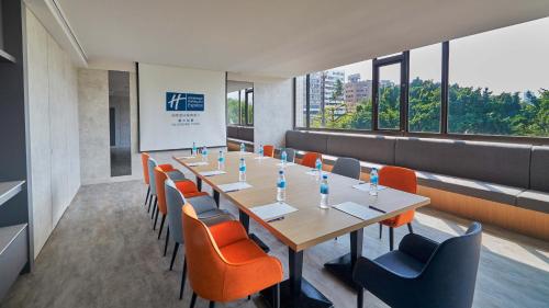 a conference room with a long table and orange chairs at Holiday Inn Express Taichung Park by IHG in Taichung