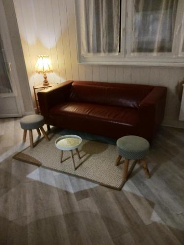a living room with a brown leather couch and two tables at Appartement confortable in Dreux