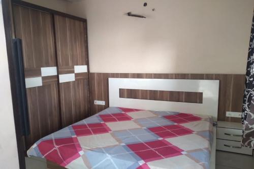 1 dormitorio con 1 cama con manta a cuadros en POP Shine Properties en Ludhiana