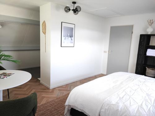 a white bedroom with a bed and a table at Guesthouse at the Amstel river with 2BR 2BA and garden in Amstelveen