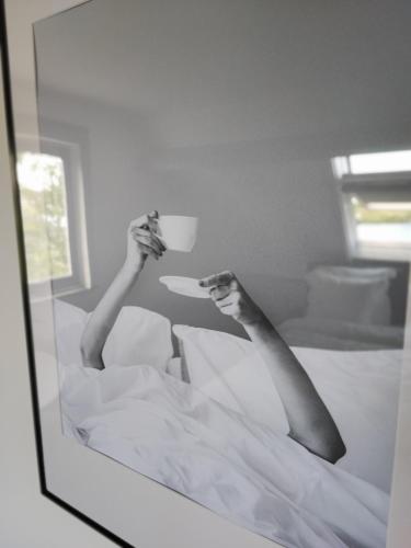 a person laying in bed holding a cup of coffee at Guesthouse at the Amstel river with 2BR 2BA and garden in Amstelveen