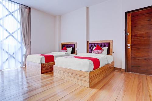 two beds in a room with wooden floors at Capital O 90428 Remington Hotel in Palembang
