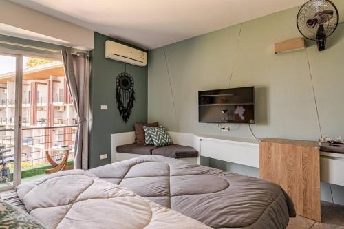 een slaapkamer met een groot bed en een televisie bij Dreamcatcher Condo/ Replay Condominium in Bophut 