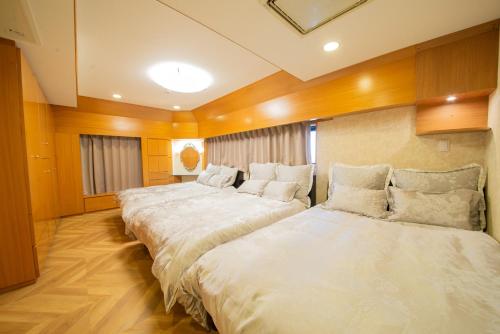 2 Betten in einem Zimmer mit Holzwänden und Holzböden in der Unterkunft NY Cottage（コテージ） in Tokio