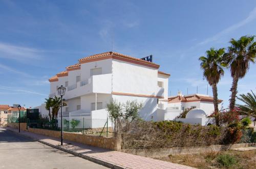 a white building with palm trees in front of a street at Hostal Manolo in Garrucha