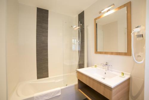 a bathroom with a sink and a tub and a mirror at Hôtel An Ti Gwenn in Carnac