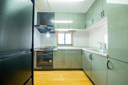 a kitchen with stainless steel appliances and a black refrigerator at NY Cottage（コテージ） in Tokyo