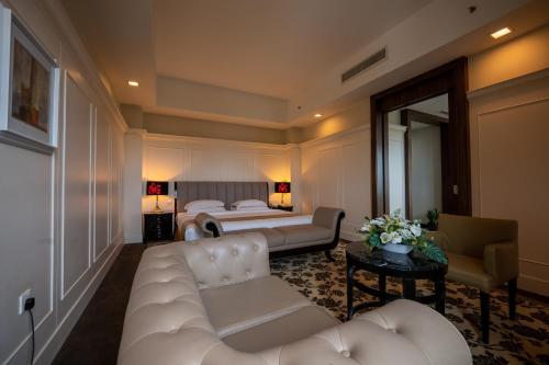 a living room with a white couch and a bed at Crown Garden Hotel in Kota Bharu