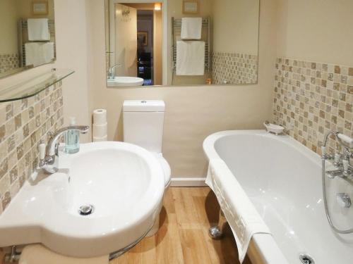 a bathroom with a white tub and a sink at The Old Clockmakers in Pateley Bridge