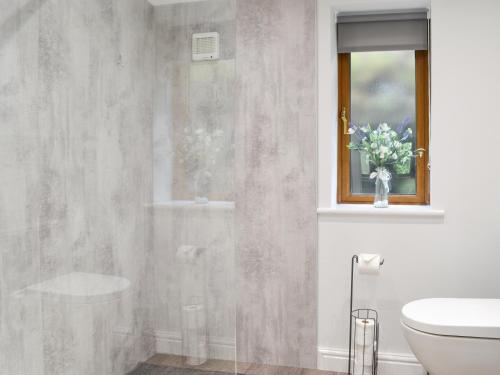 a bathroom with a toilet and a vase of flowers at Kimberdale Lodge in Great Orton