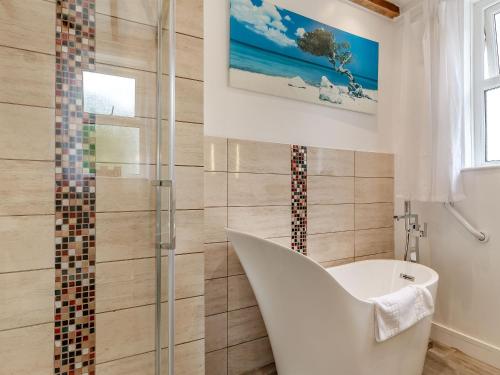 een badkamer met een wit bad en een douche bij Shoreline in Goodrington