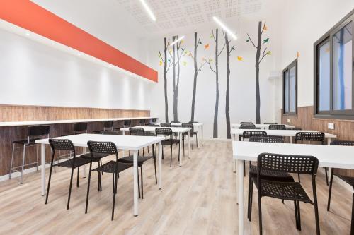 a dining room with tables and chairs and trees on the wall at Ant Hostel Barcelona in Barcelona