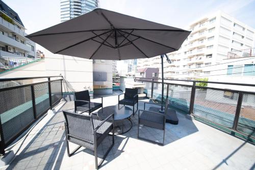 a balcony with a table and chairs and an umbrella at NY Cottage（コテージ） in Tokyo