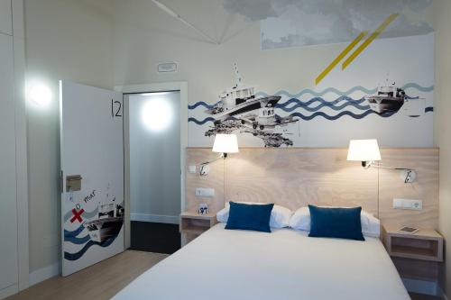 um quarto com uma grande cama branca com almofadas azuis em Hotel Tematico Do Banco Azul em Finisterre