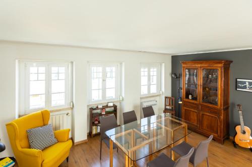 a living room with a glass table and a yellow chair at Ambassador River Shower Suites in Lisbon