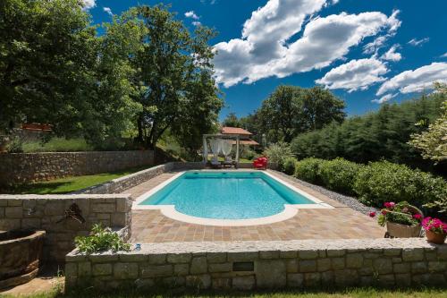 a swimming pool in a garden with a stone wall at 9b-The Resort in Sežana