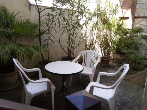 3 chaises blanches, une table, une table et des chaises dans l'établissement HERM'S Petite maison atypique et cour privative -, à Cabourg