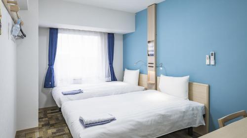 Toyoko Inn Kita-asaka-eki Nishi-guchi في Asaka: سريرين في غرفة بجدران زرقاء ونافذة