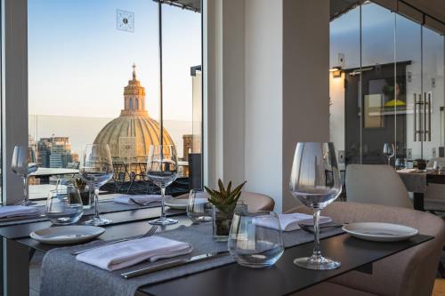 a table with wine glasses and a view of the city at The Embassy Valletta Hotel in Valletta
