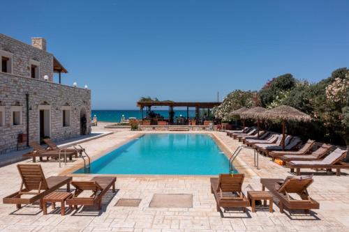 a swimming pool with lounge chairs and the ocean at Avgerinos Village in Agiassos