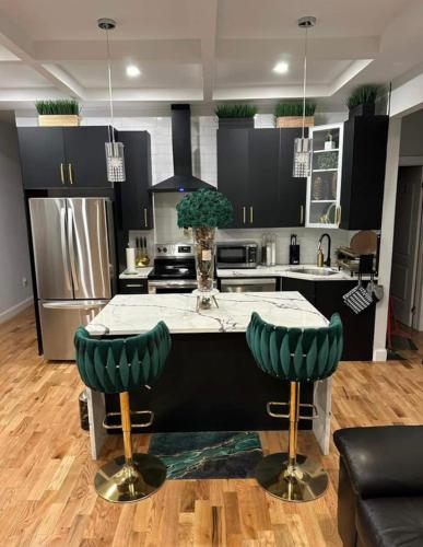 a kitchen with black cabinets and a table with green chairs at STEPH VACATION HOME in Brooklyn