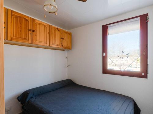 um pequeno quarto com uma cama e uma janela em Appartement Gruissan, 3 pièces, 6 personnes - FR-1-409A-15 em Gruissan